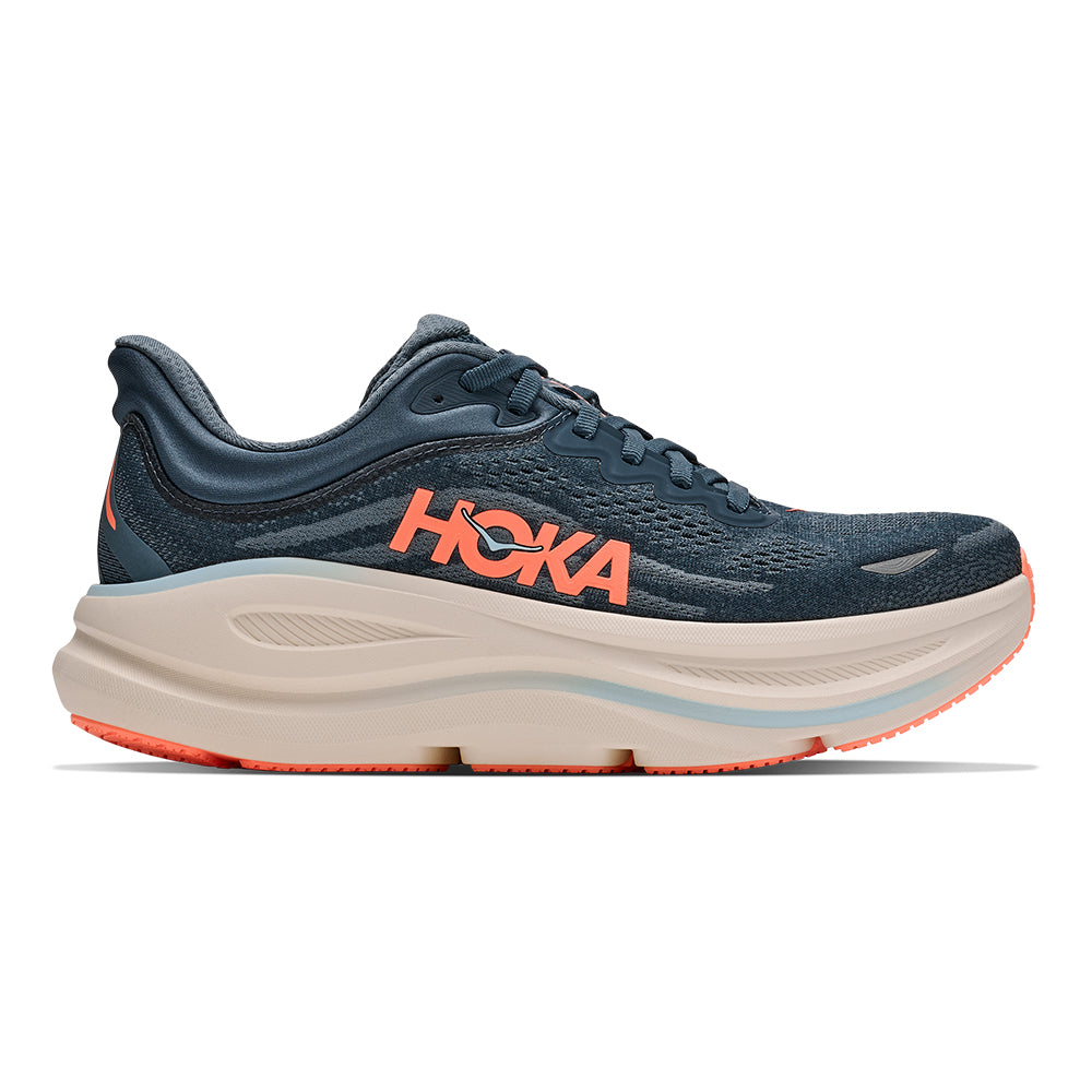 A HOKA running shoe in navy blue with a thick beige midsole and bright orange accents, including the HOKA logo and outsole details, shown from a side profile on a white background.